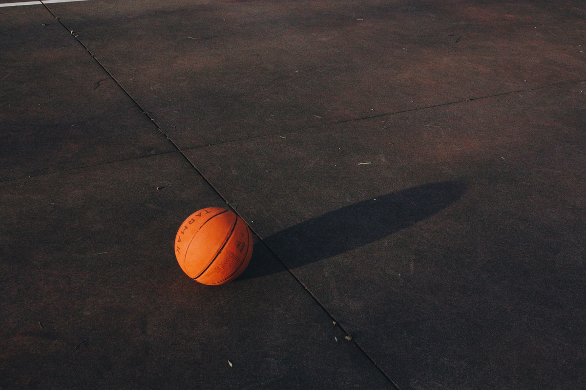 Basketball resting on a dark outdoor court at dusk