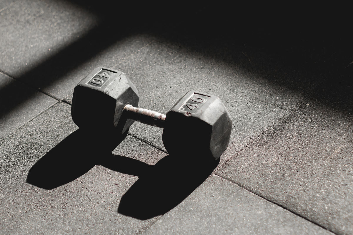 Hex dumbbell in a beam of light on a dark gym floor
