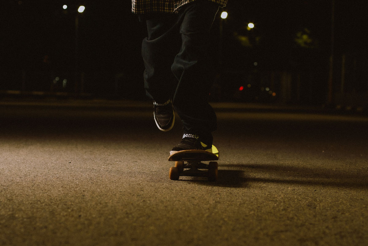 Skateboarder rolling along a dark street at night
