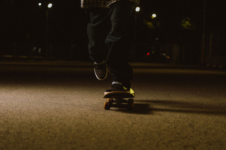 Skateboarder rolling along a dark street at night
