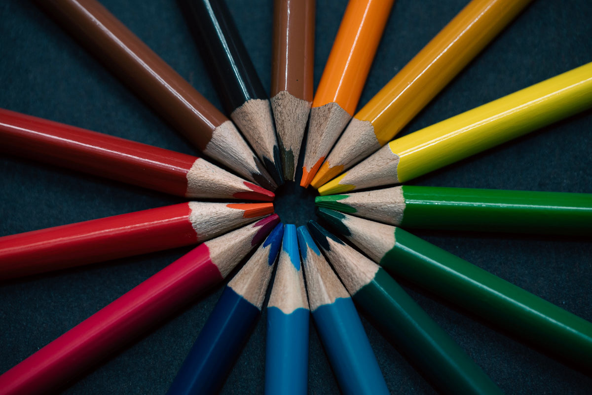 Coloured pencils arranged in a circle on a dark surface