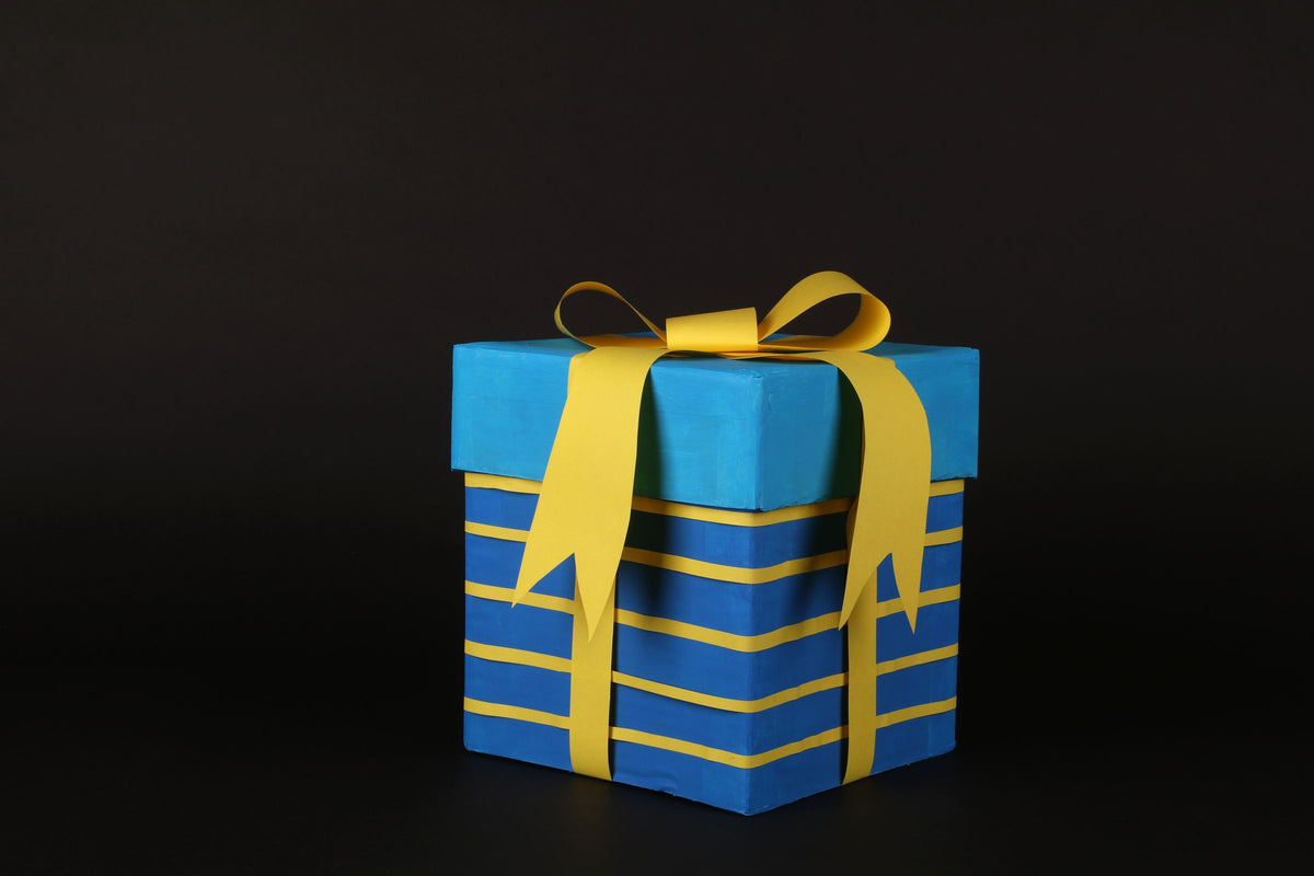Wrapped blue gift box with a yellow ribbon on a dark background