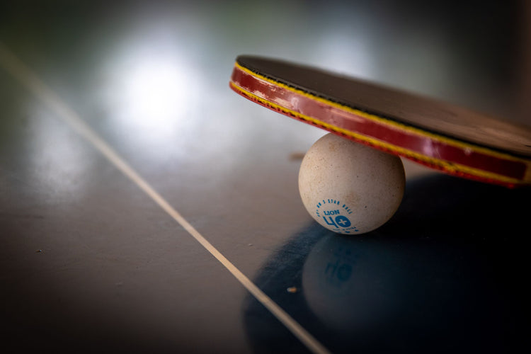 Table tennis paddle balanced on a ball on a black table