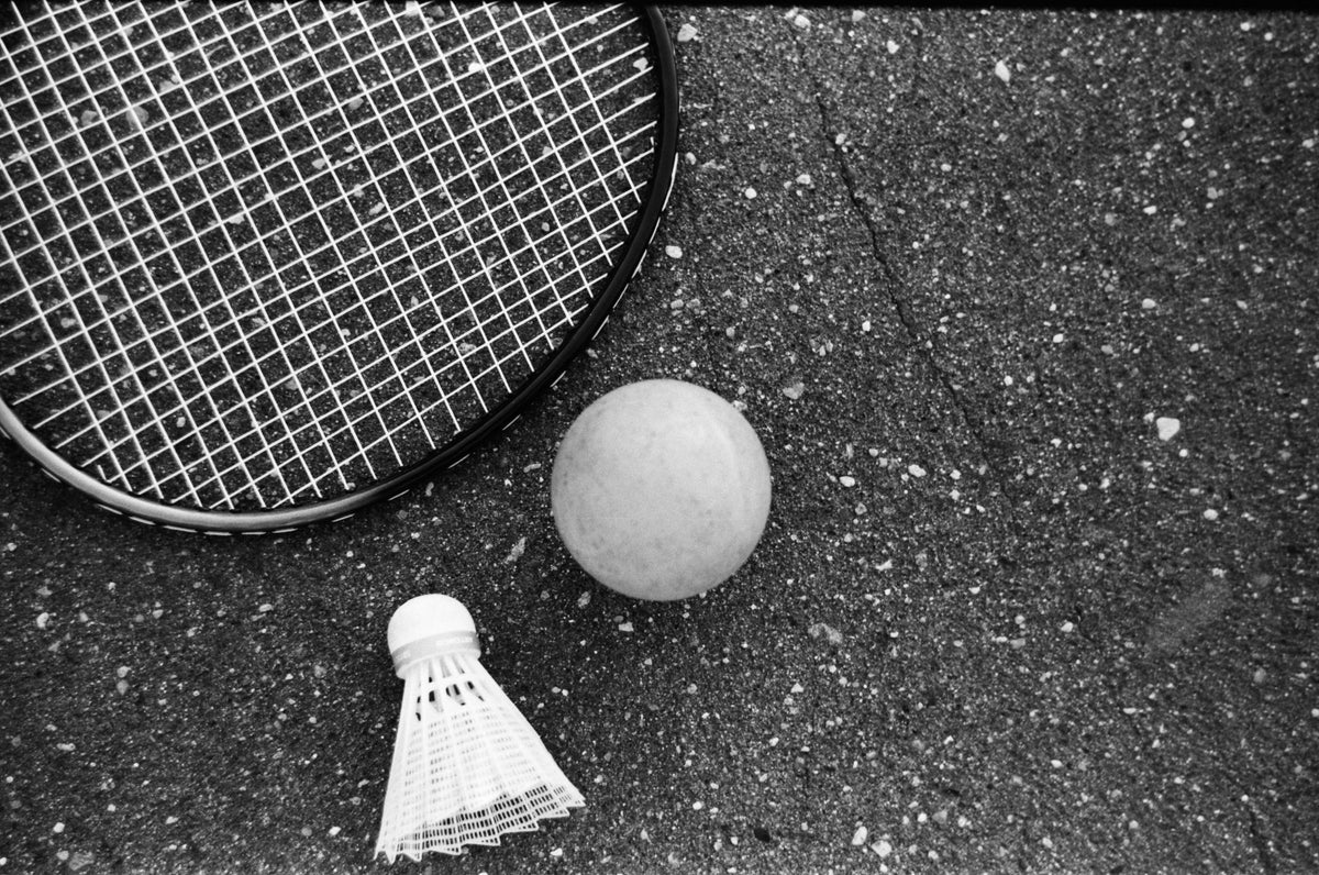 Racket, ball and shuttlecock on dark asphalt