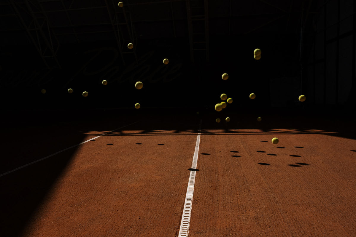 Tennis balls bouncing on a court under dramatic low light
